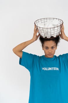 African American woman volunteering, holding a basket of disposable cups highlighting environmental conservation.