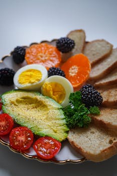 Vibrant breakfast plate with fresh avocado, eggs, and assorted fruits.