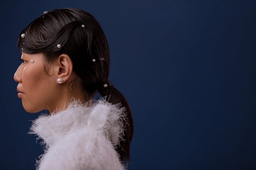 Elegant portrait of a woman with pearl-adorned hairstyle against a blue background.